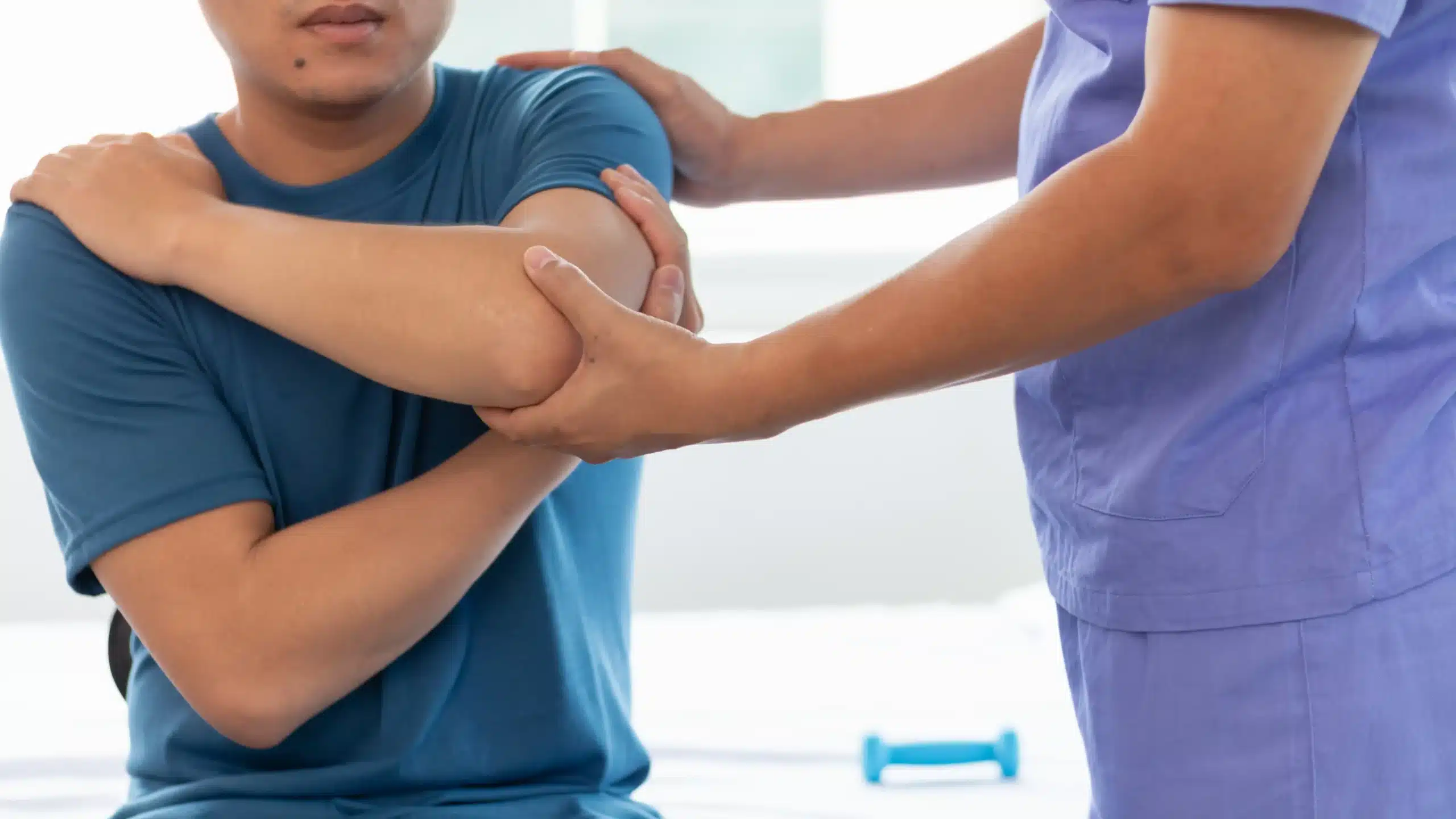 Doctor treating a man for back and shoulder muscle pain caused by overtraining in the gym.